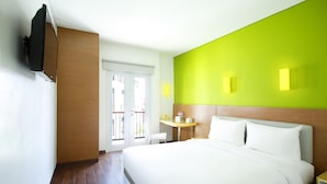Una habitación de hotel con una cama, un escritorio, una silla y un televisor fijado a la pared.