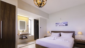 Una habitación de hotel moderna con una cama grande, lámparas de noche, una tocador con espejo y obras de arte en la pared.