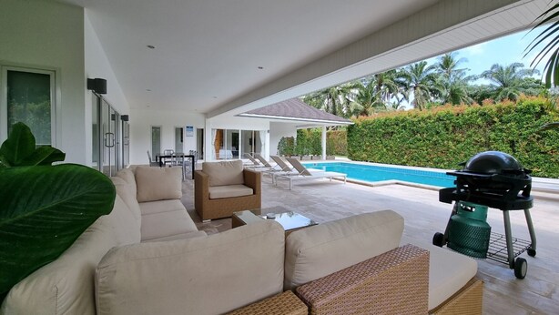 Un espacio exterior moderno con piscina, sillas de descanso y una parrilla.