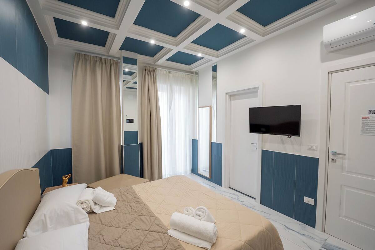 Een hotelkamer met een bed, een aan de muur bevestigde televisie en een deur.