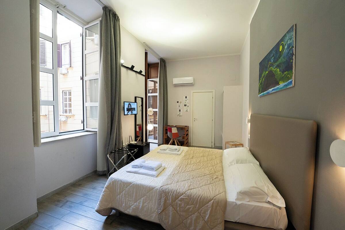 Een hotelkamer met een bed, een bureau, een stoel, een televisie en een schilderij aan de muur.