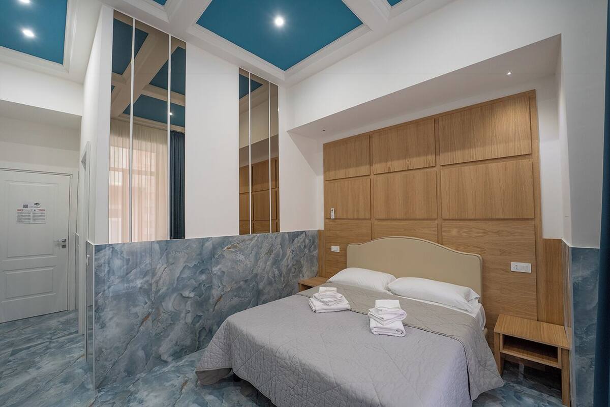 Een slaapkamer met een bed, een houten hoofdeinde, een marmeren wand en een deur.