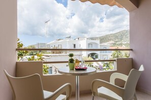 Un balcon avec deux chaises, une petite table et un pot de fleurs.