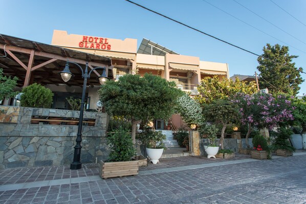Un hôtel appelé « Hôtel Glaros », doté d’une façade en pierre, de nombreux balcons et de plantes en pot.