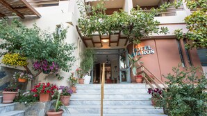 A hotel entrance with a marble staircase, potted plants, and a sign reading "HOTEL CARLOS".