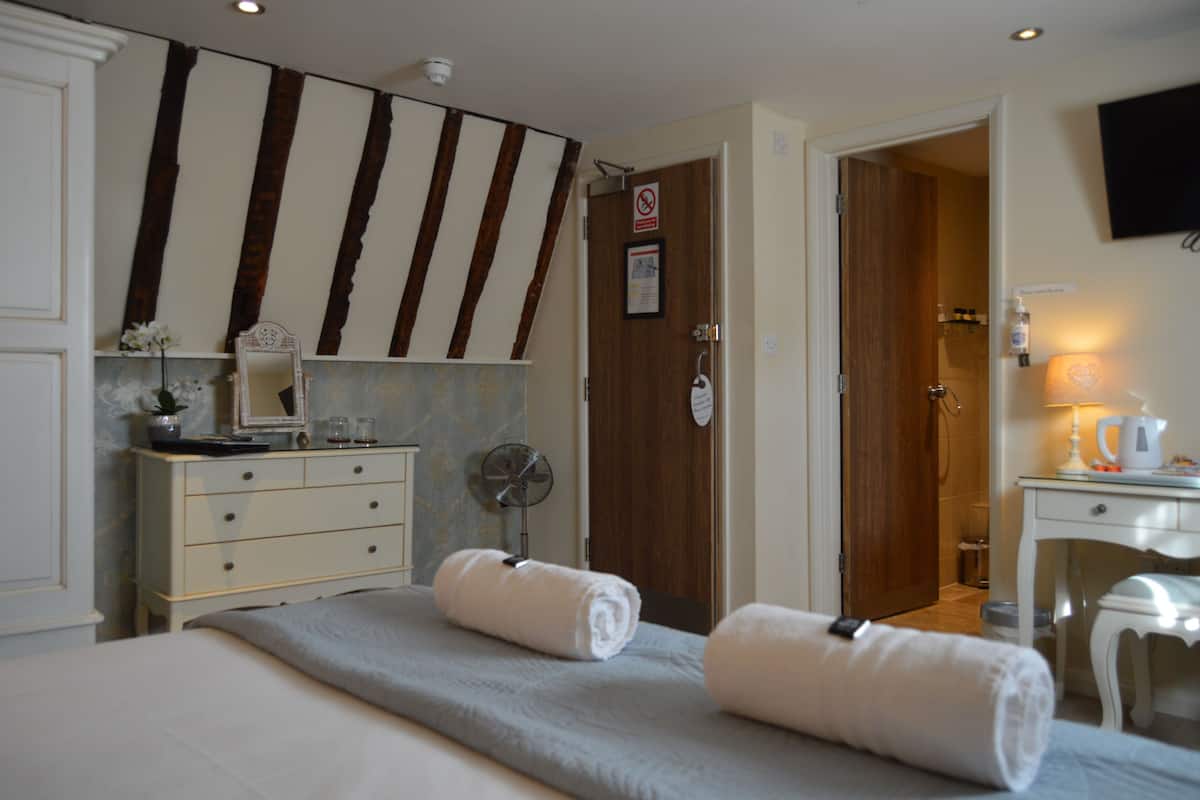 Habitación de hotel con cama, cómoda, espejo, ventilador, escritorio y televisor.