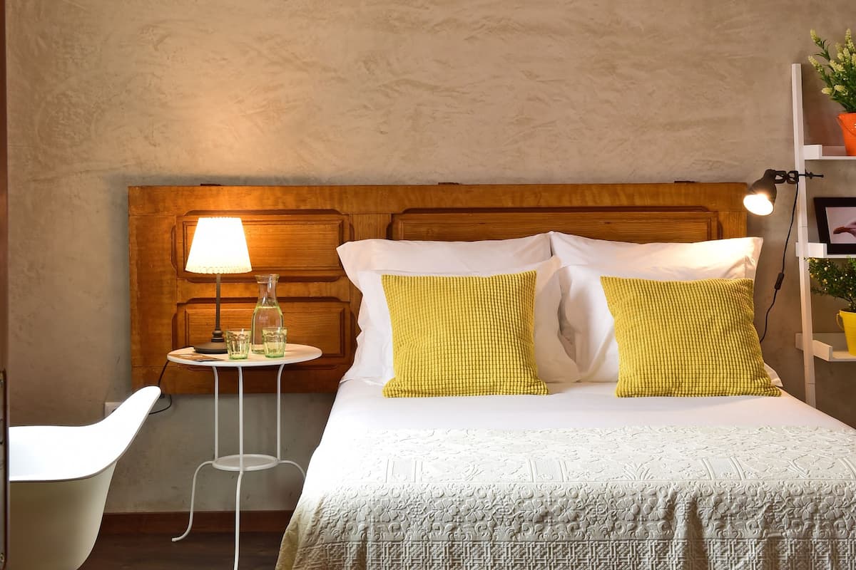 Une chambre à coucher bien rangée, avec une tête de lit en bois, une table de chevet avec une lampe et une chaise.