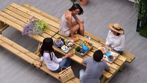A group of people seated at a wooden table with various food items and drinks. - Mercearia d'Alegria Boutique B&B (Peniche)