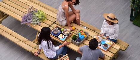 A group of people seated at a wooden table with various food items and drinks.