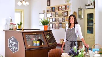 A vintage-style counter with a sign reading "Merceria d'Alegrias," a potted plant, and various items on display.