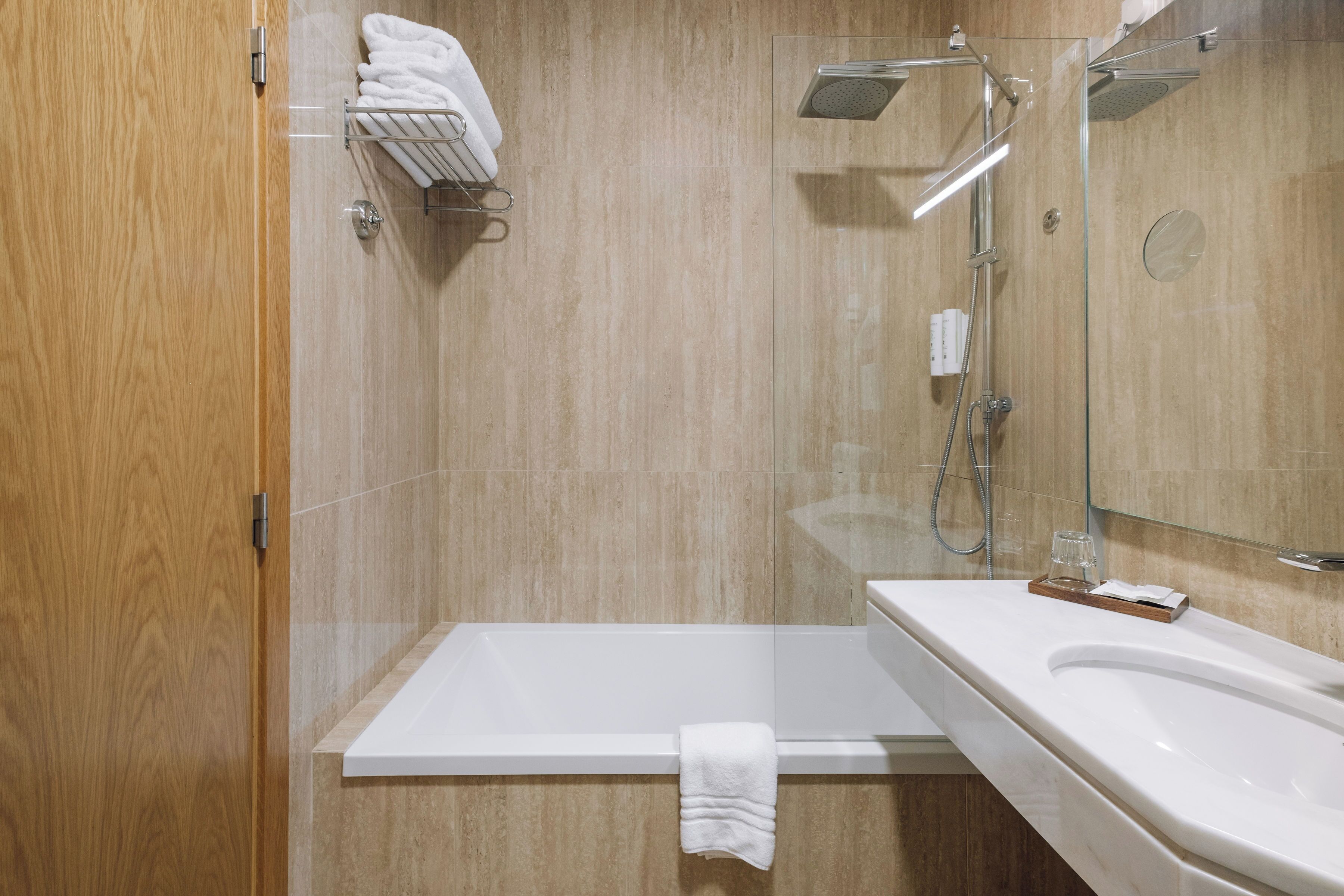 Un baño moderno con ducha de vidrio, una bañera blanca y un tocador con espejo.