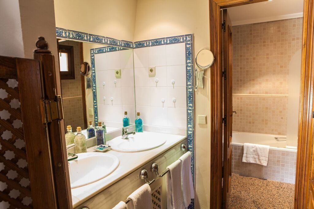 A bathroom with two sinks, a mirror, and a bathtub.