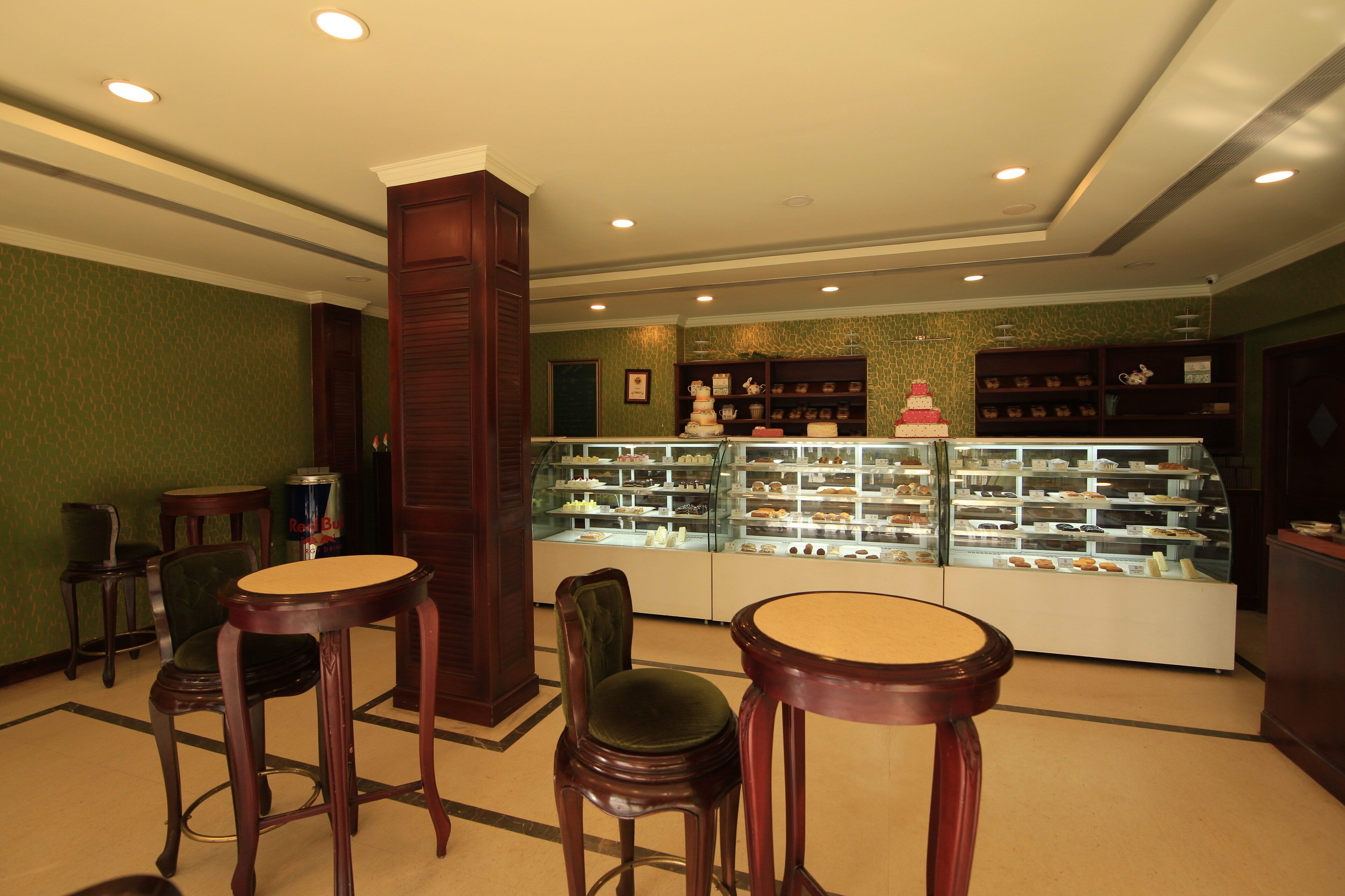 Un escaparate de panadería con diversos productos horneados, sillas de madera y una vitrina de vidrio.