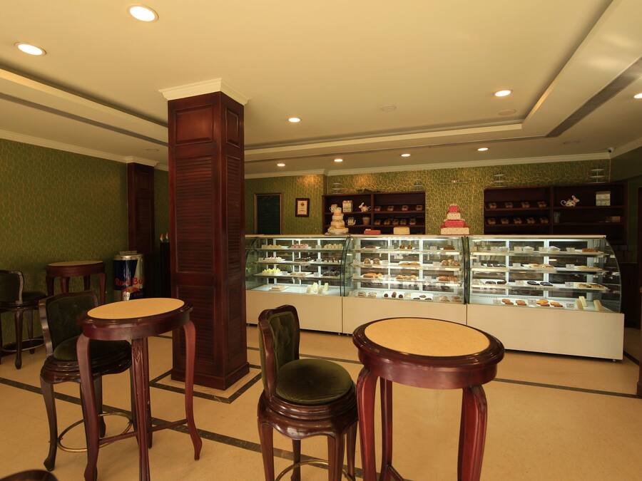 Un escaparate de panadería con diversos productos horneados, sillas de madera y una vitrina de vidrio.