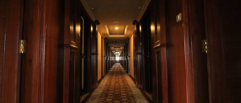 A long, narrow hallway with wooden doors on both sides and a patterned carpet.