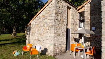 A stone building with a small patio area featuring outdoor seating and a table with chairs.