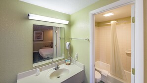 A bathroom with a sink, mirror, and a shower area.