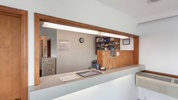Una recepción con estructura de madera, un reloj y un cartel que indica los horarios de registro.