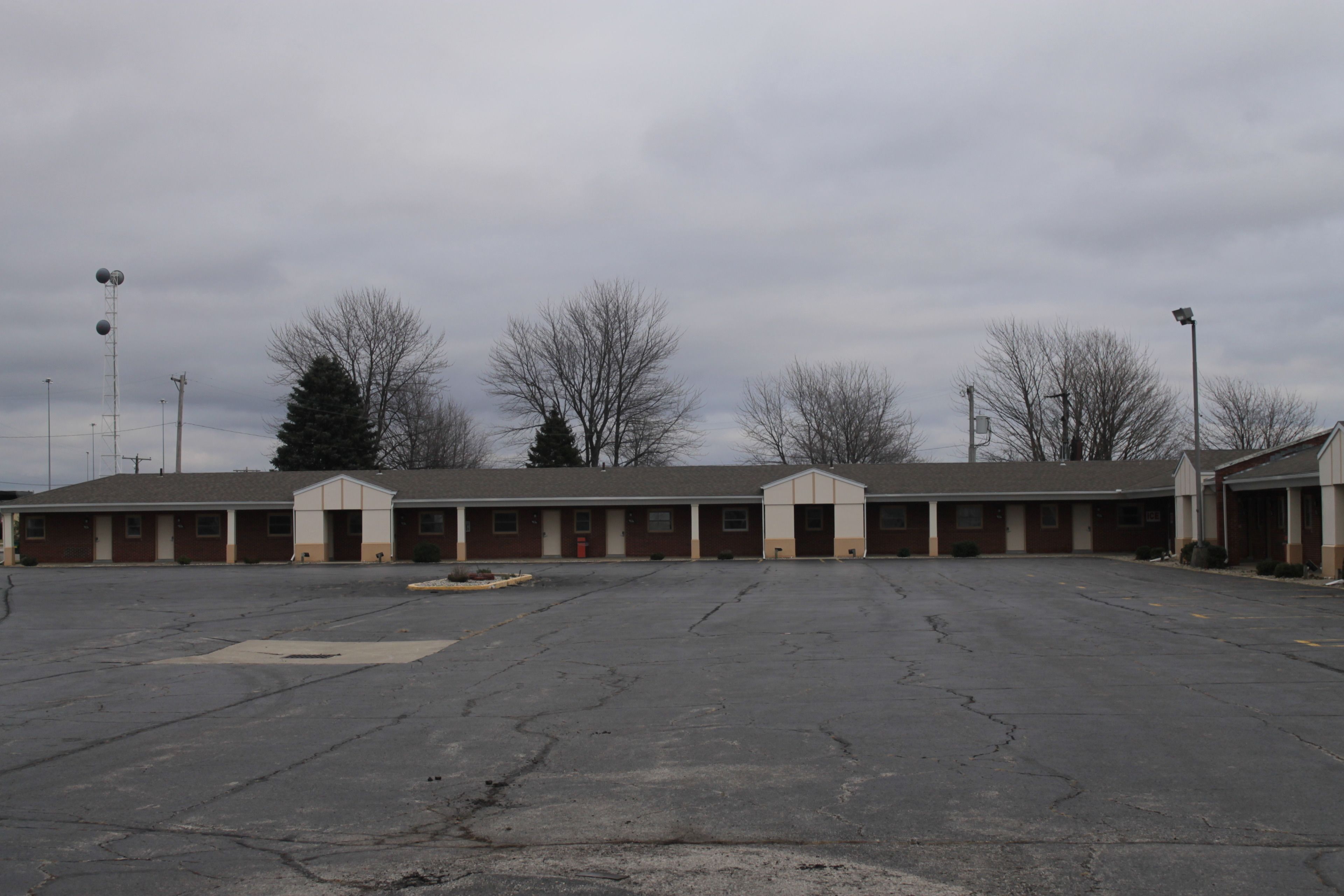 Un grand parking désert situé devant un motel comprenant de nombreuses chambres.