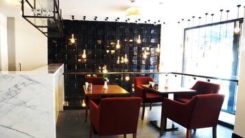 Ein modernes Restaurant mit Marmorarbeitsplatten, roten Sitzmöglichkeiten und einer schwarzen Wand mit hängenden Lampen.