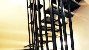 Escadaria moderna com corrimãos de metal preto e degraus brancos.
