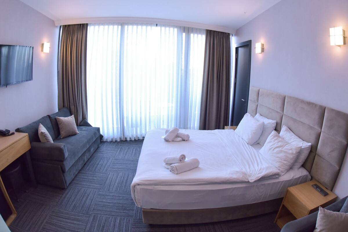 Una habitación de hotel con una cama grande, un sofá, un escritorio y un televisor.