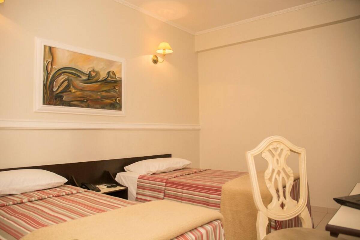 Ett hotellrum med två sängar, en stol, ett skrivbord och en tavla på väggen.