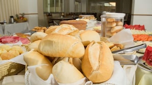 Una mesa de buffet con panes y pasteles varios, incluyendo panecillos y cruasanes, además de un recipiente con galletas.