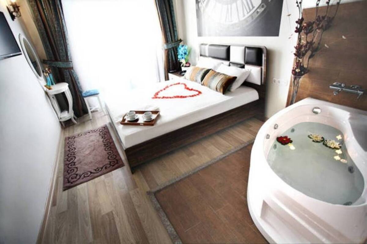Une chambre d’hôtel moderne avec un grand lit, une salle de bain avec baignoire et un plancher en bois.
