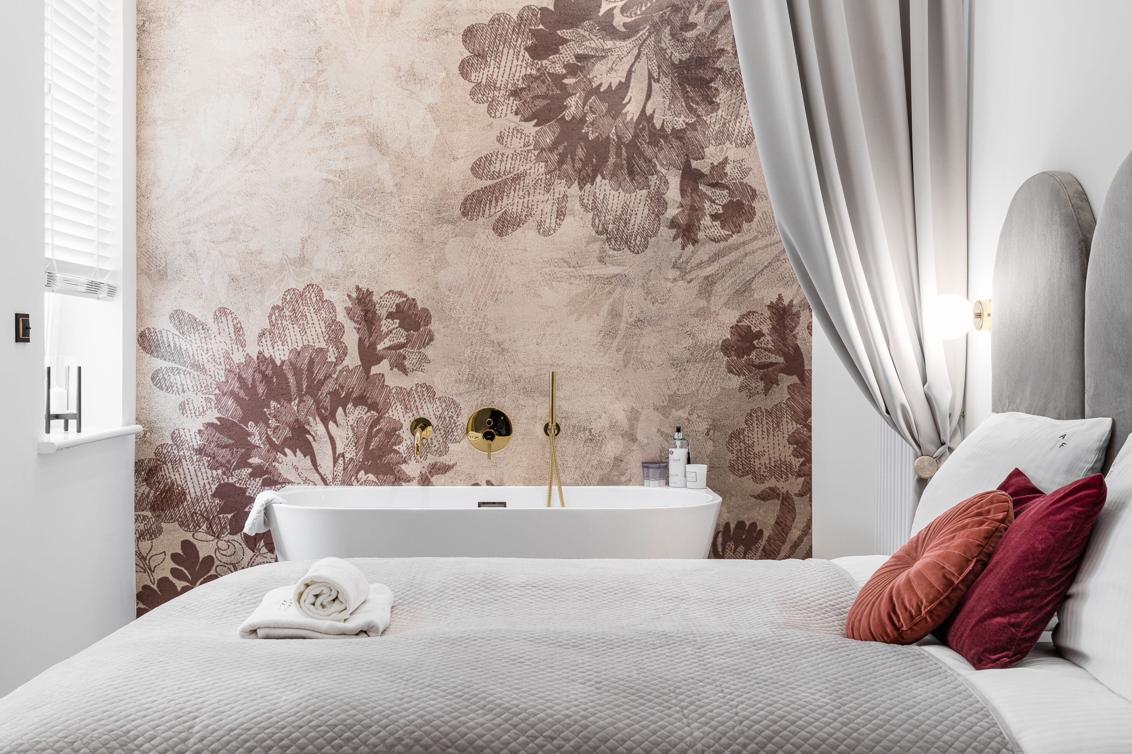 A modern bathroom with a freestanding bathtub, a towel on the bed, and a shower control panel.