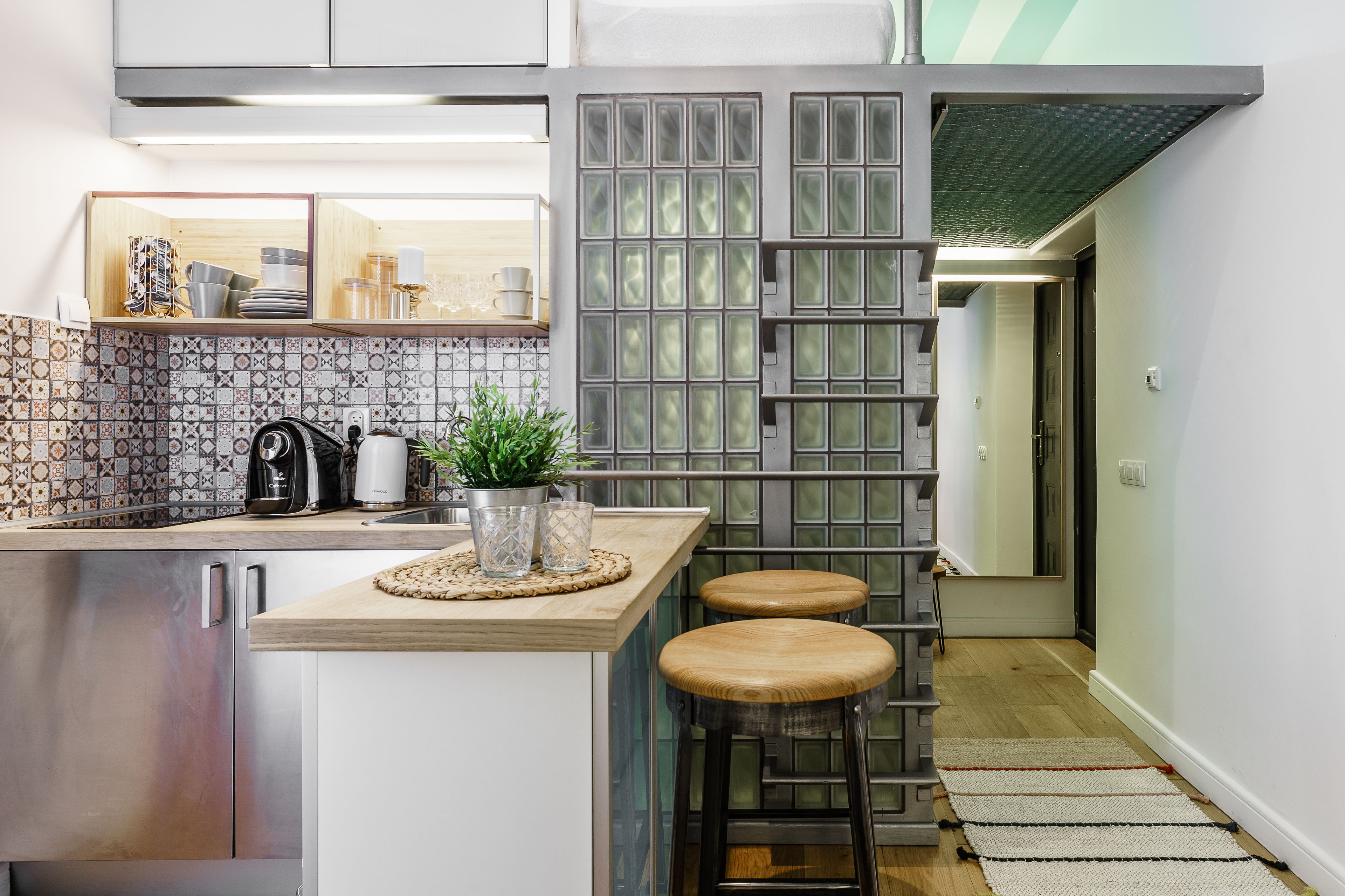 A modern kitchen with a wooden countertop, stainless steel appliances, and a decorative plant.