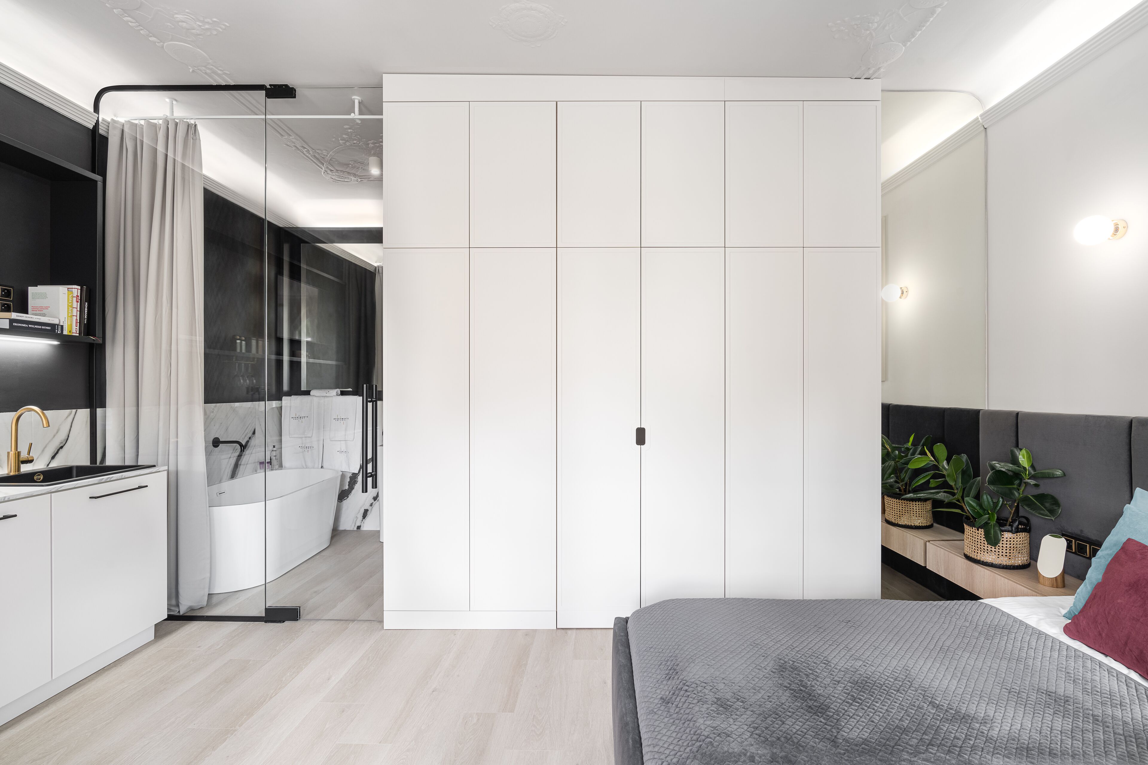 Un dormitorio moderno con cama, mesita de noche y un espejo grande.