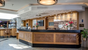 Un lobby moderno de hotel con mostrador de recepción, área de bar y asientos.