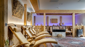 Un espacio de spa con sillones de madera, chimenea de piedra y una alfombra tradicional.