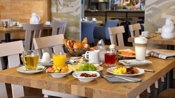Una mesa de desayuno con diversos platos, bebidas y un periódico.