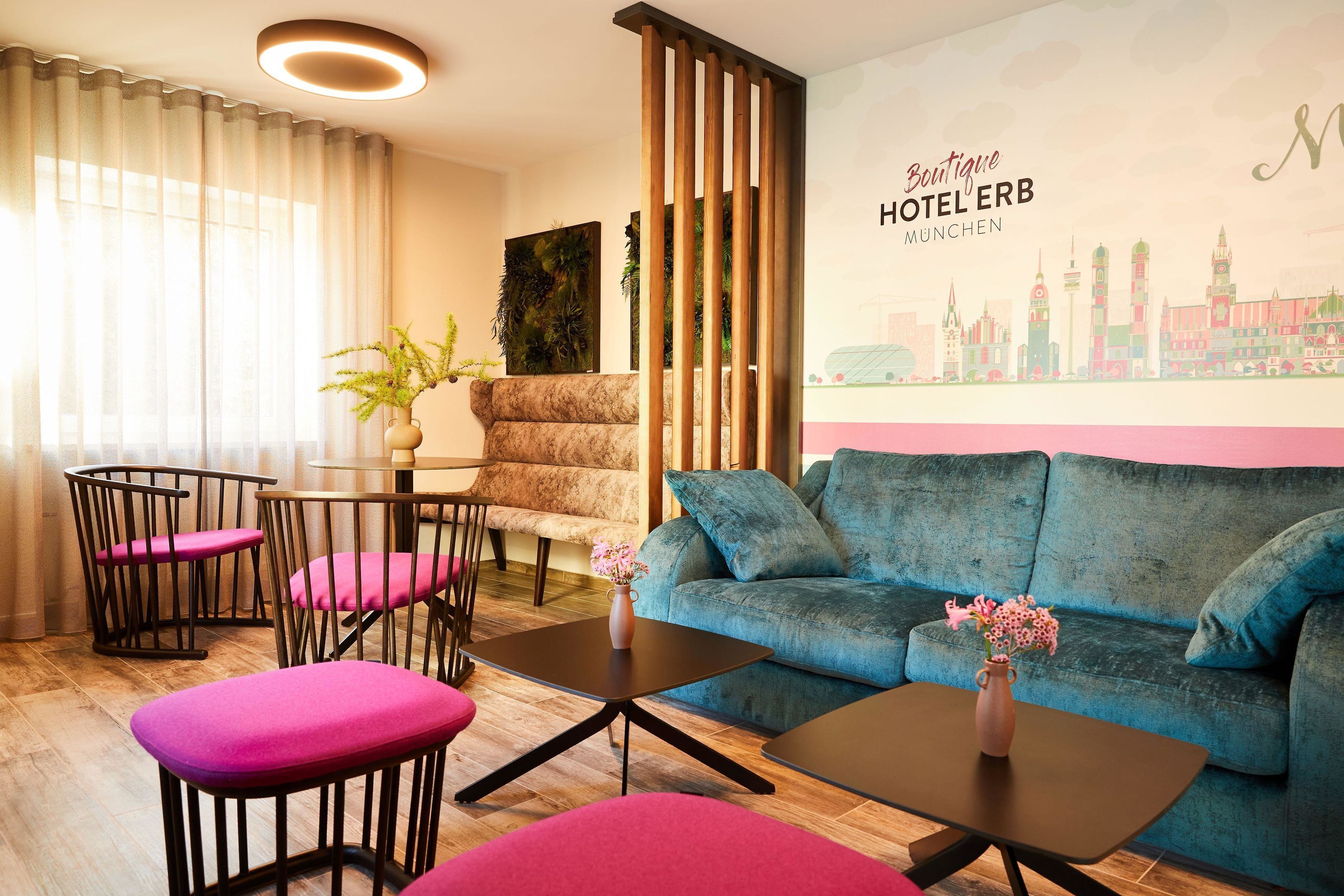 A modern hotel room with a blue sofa, pink chairs, a small table, and a cityscape mural.