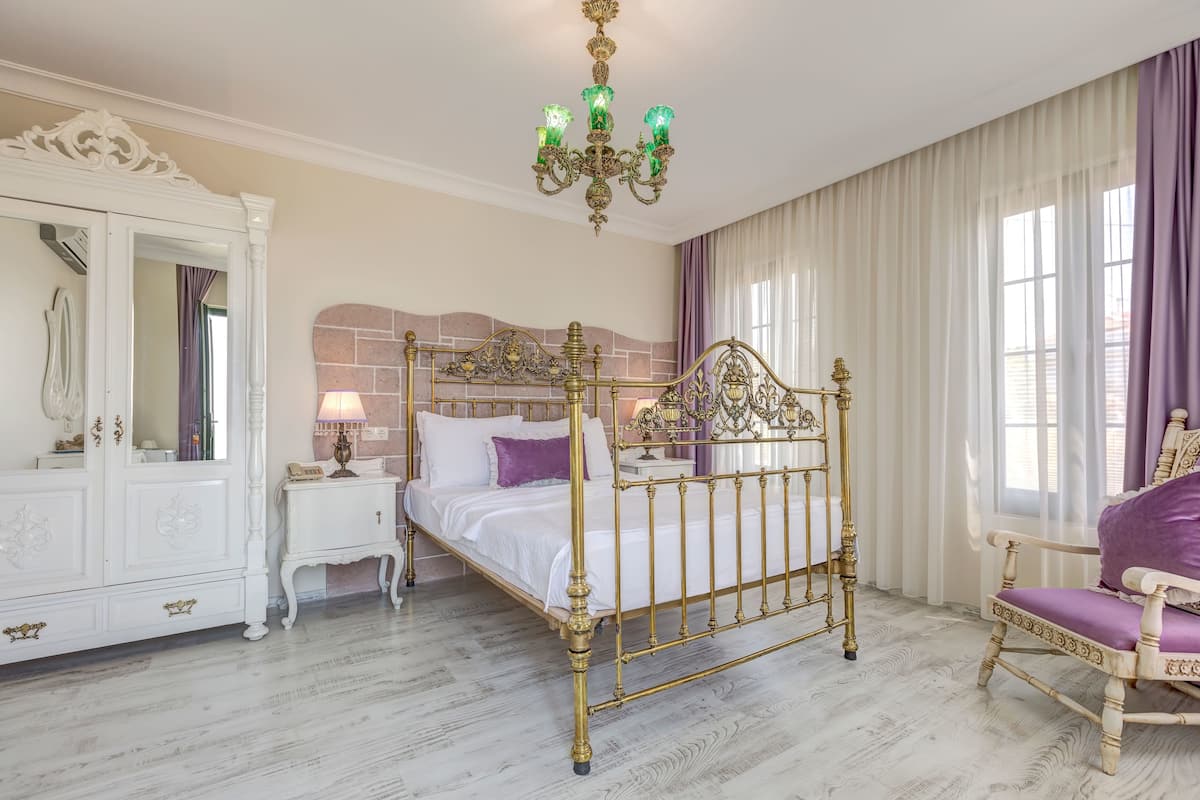 Una habitación con una cama con dosel, un armario blanco, una tocador con espejo y un candelabro.