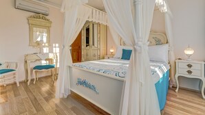 Une chambre à coucher avec un lit à baldaquin, une coiffeuse avec un miroir, un bureau et une table de chevet.