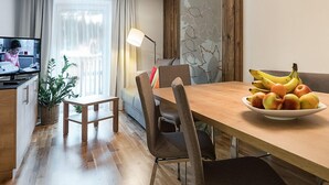 Una sala de estar moderna con una mesa de comedor de madera, un sofá, un televisor y un cuenco de frutas.