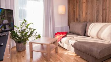 Una sala de estar moderna con una pared de madera, un sofá, un televisor, una planta y una lámpara.