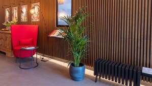 Un interior moderno con una silla roja, una planta en maceta y un radiador.