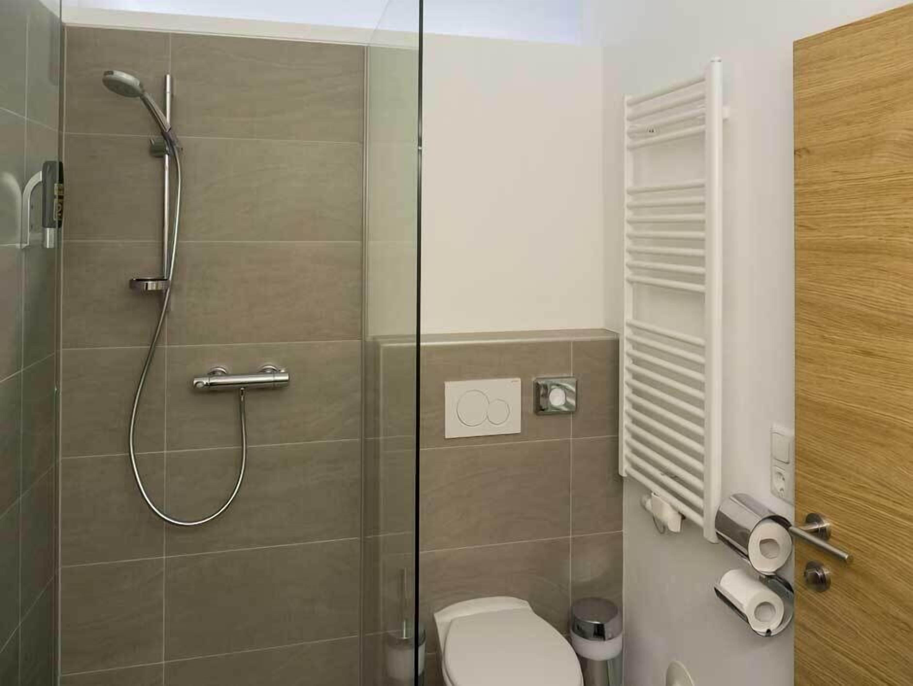 Un bagno moderno con doccia vetro, un water e un portascopevoli.