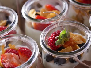 A close-up of several glass jars containing layered desserts with fruits and cereal. - Der Brückenwirt (Heinfels)