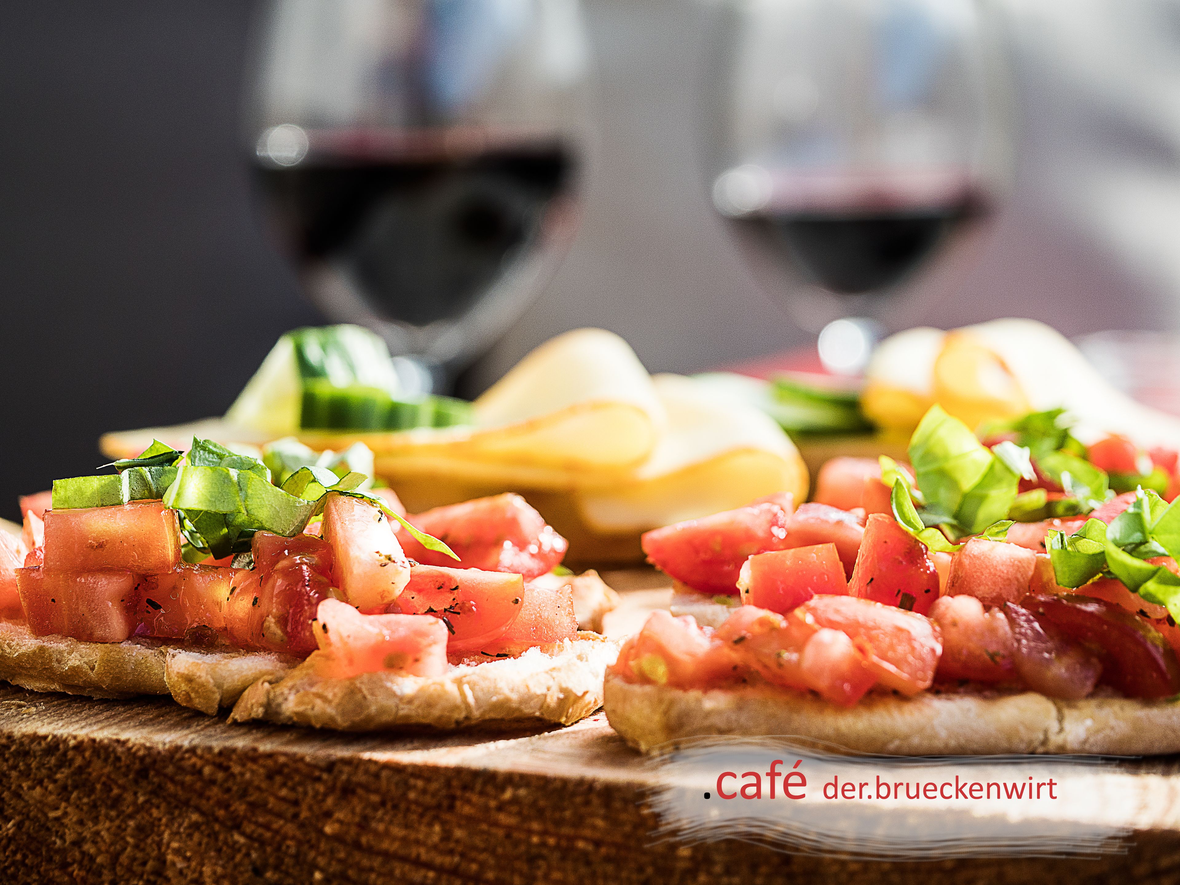 Une table en bois sur laquelle sont disposés divers aliments, notamment du pain garni et un verre de vin rouge.