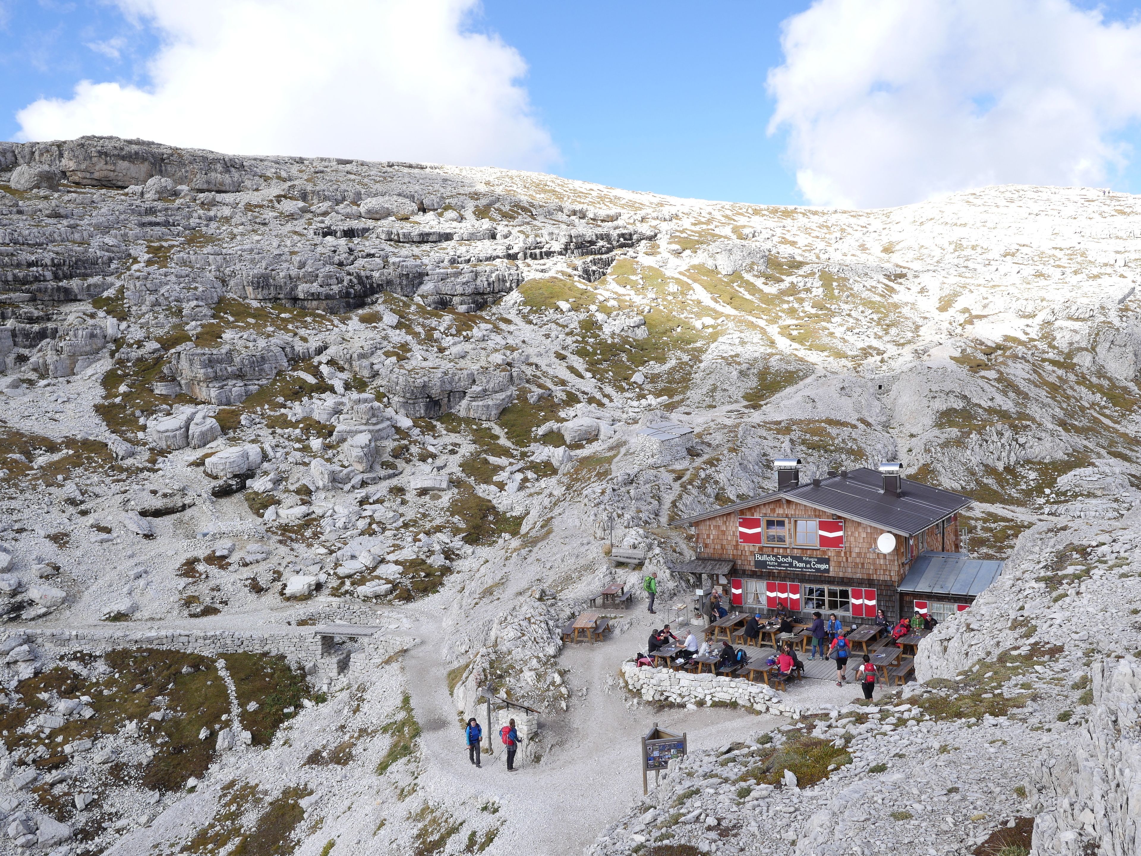 Un chalet de montagne avec une façade en bois, des sièges à l’extérieur et un ciel dégagé.