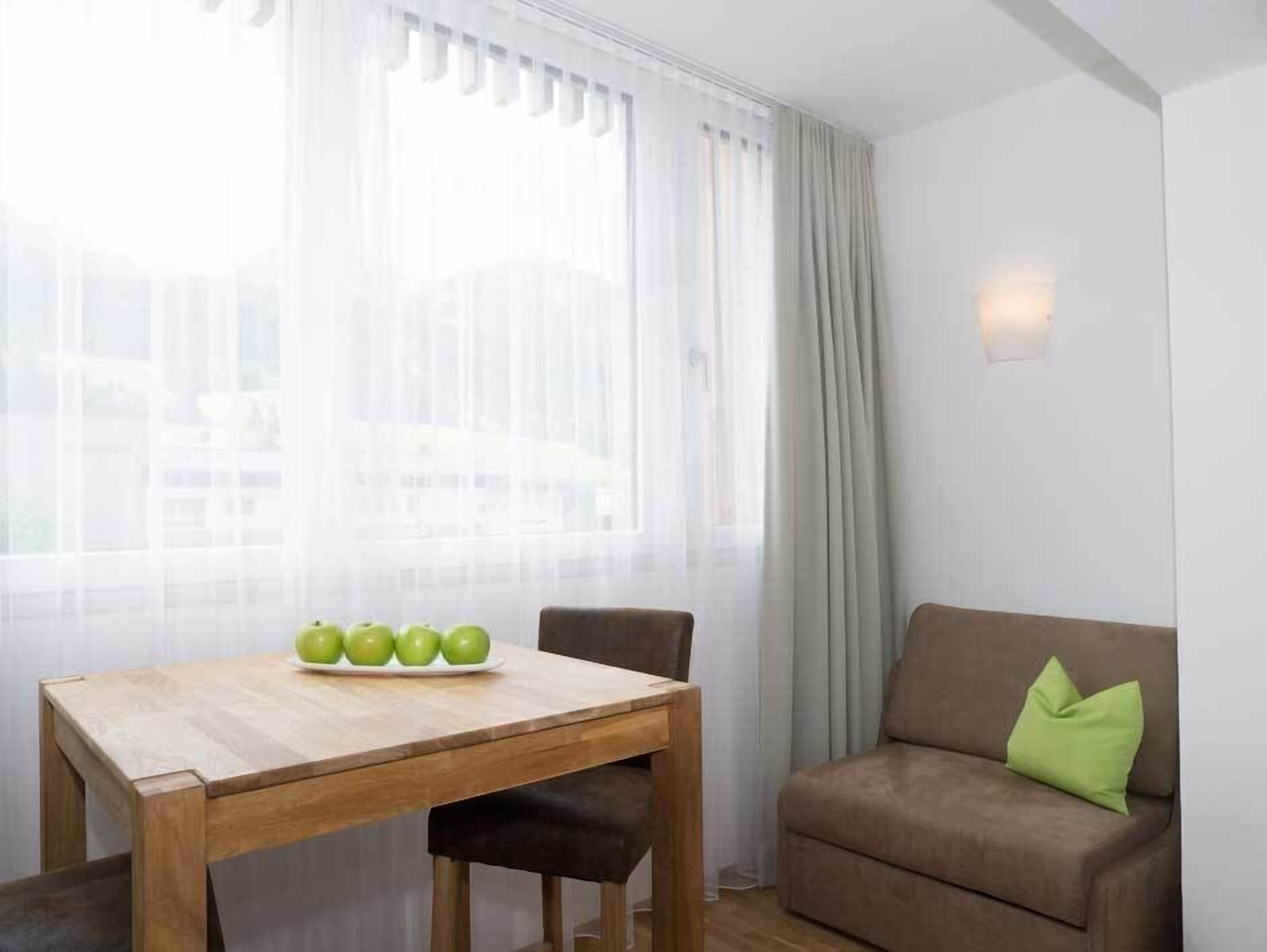 Ett rum med ett träbord, en brun soffa och en grön kudde.