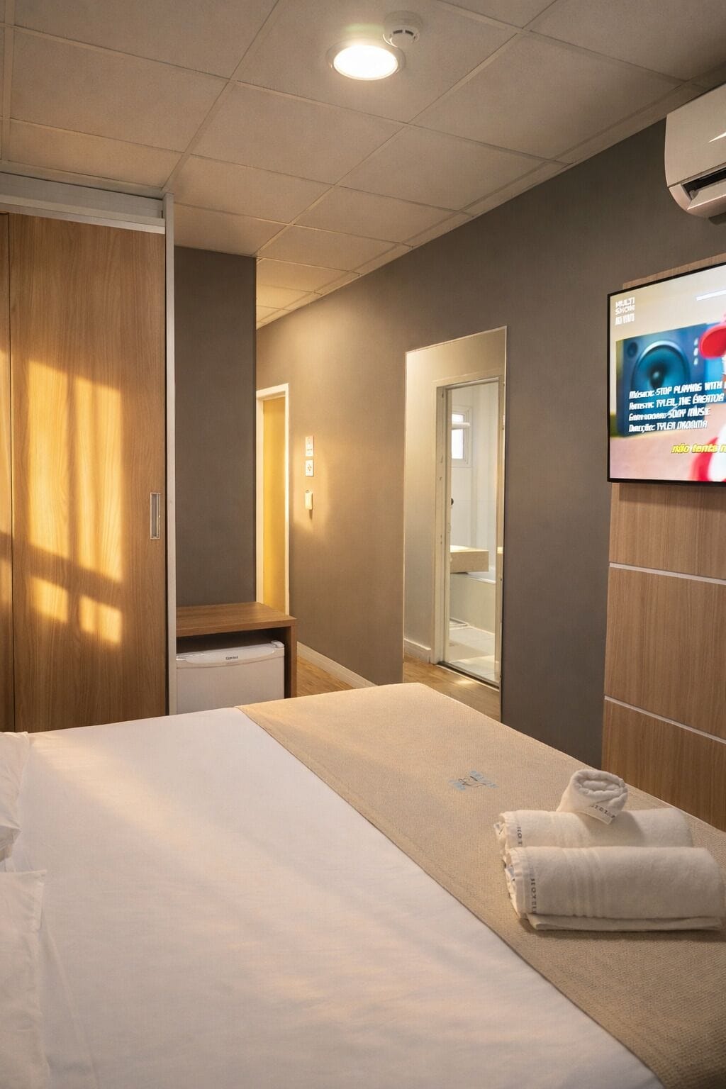 Habitació d'hotel amb llit, televisió, armari i bany.