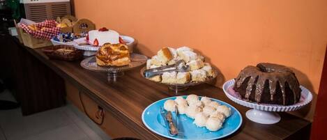 Una mesa de bufé con diversos postres y un pastel sobre un pedestal.