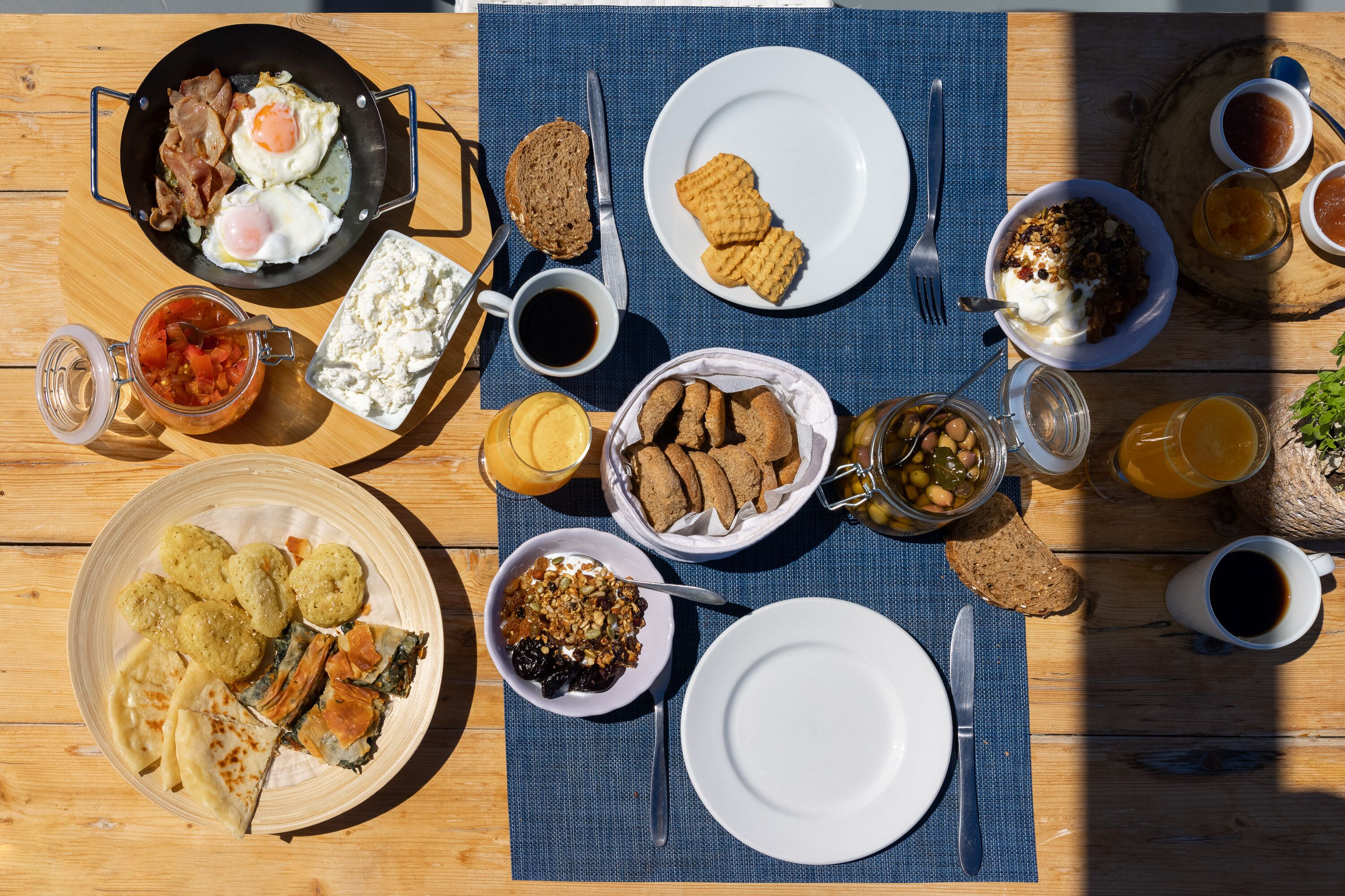 A table set with various breakfast items including eggs, bacon, bread, and beverages.
