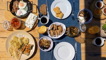 A table set with various breakfast items including eggs, bacon, bread, and beverages.